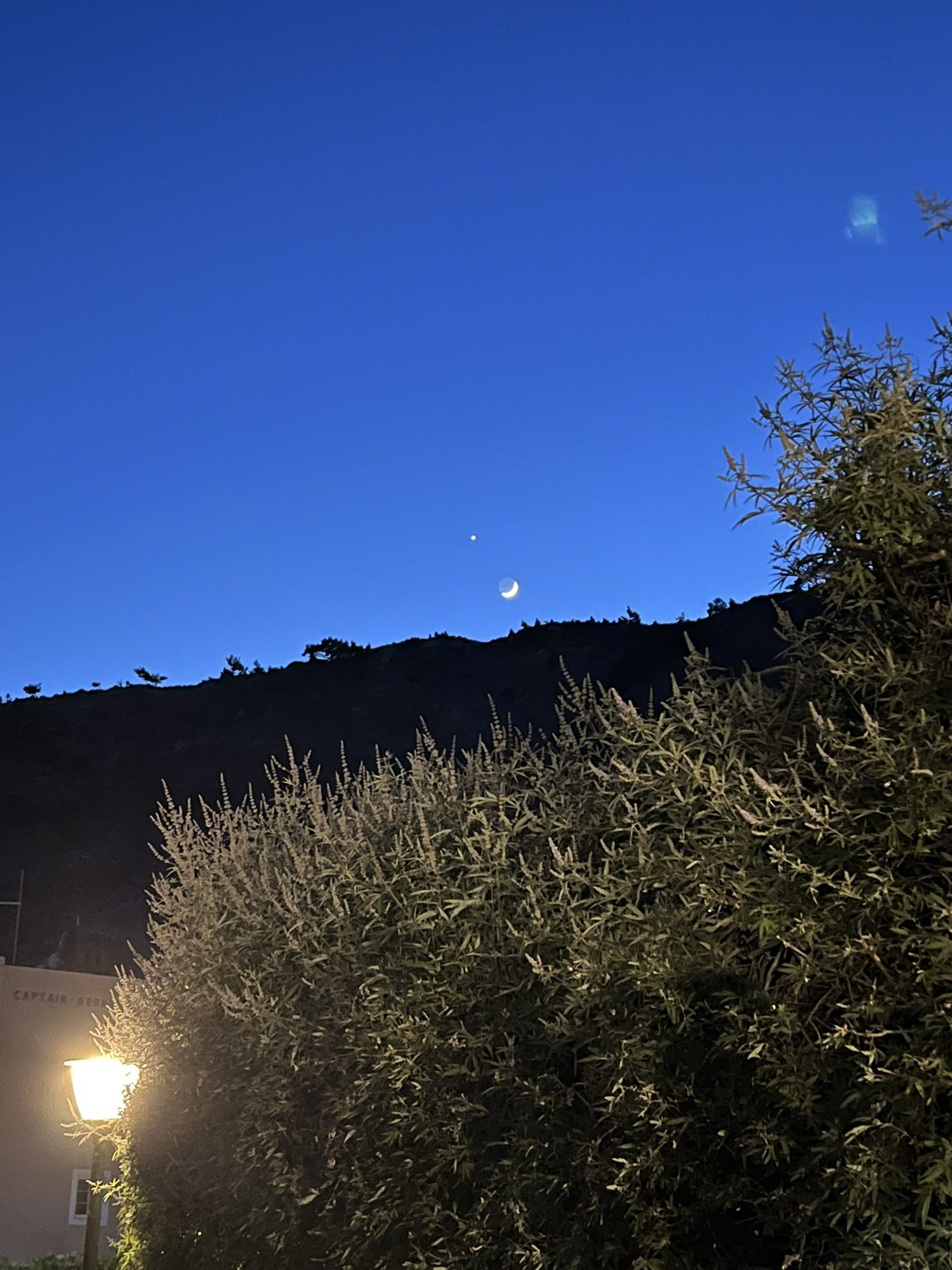 A crescent moon over the hill at nightfall