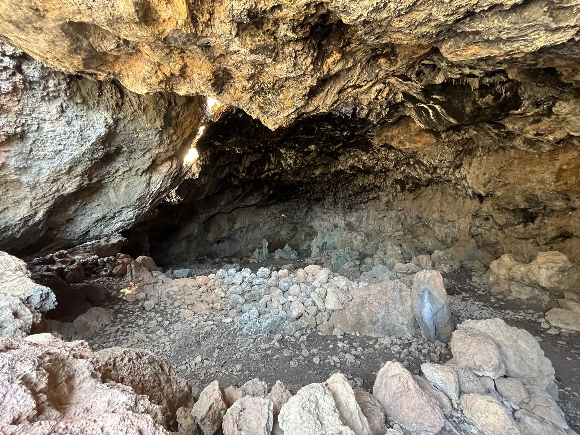 Inside the Cyclops cave, with low stone walls and the throne-like rock at the back