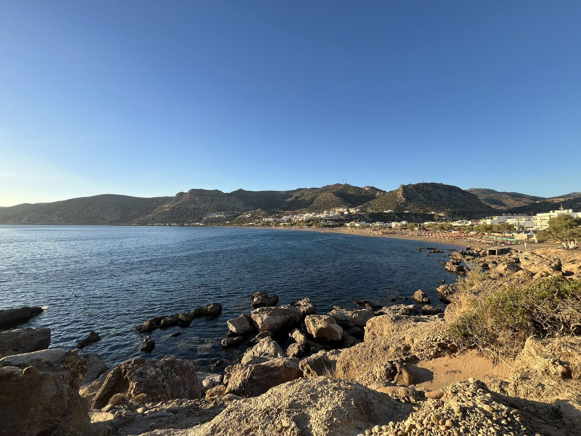 The sandy bay of Pachia Ammos in late afternoon light, seen from the rocks