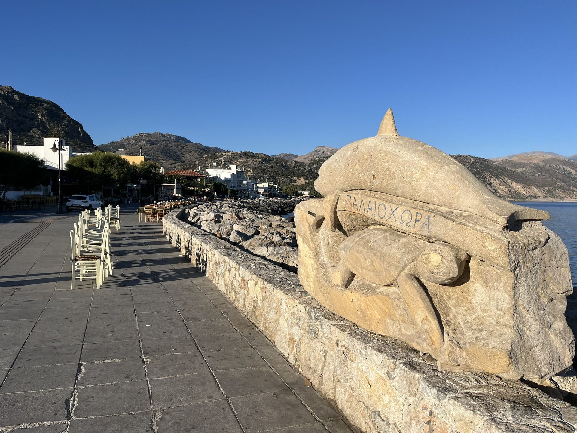 A stone dolphin and sea turtle carved with the name ΠΑΛΑΙΟΧΩΡΑ on the seafront promenade