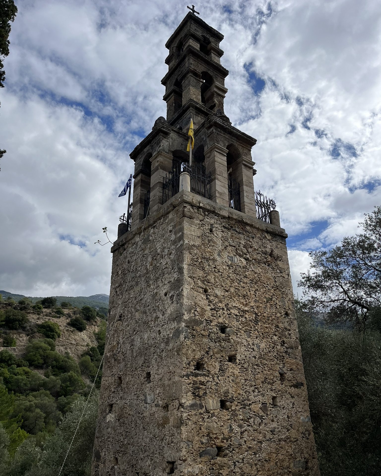 The tall stone bell tower of Panagia Kera in Moni against a cloudy sky