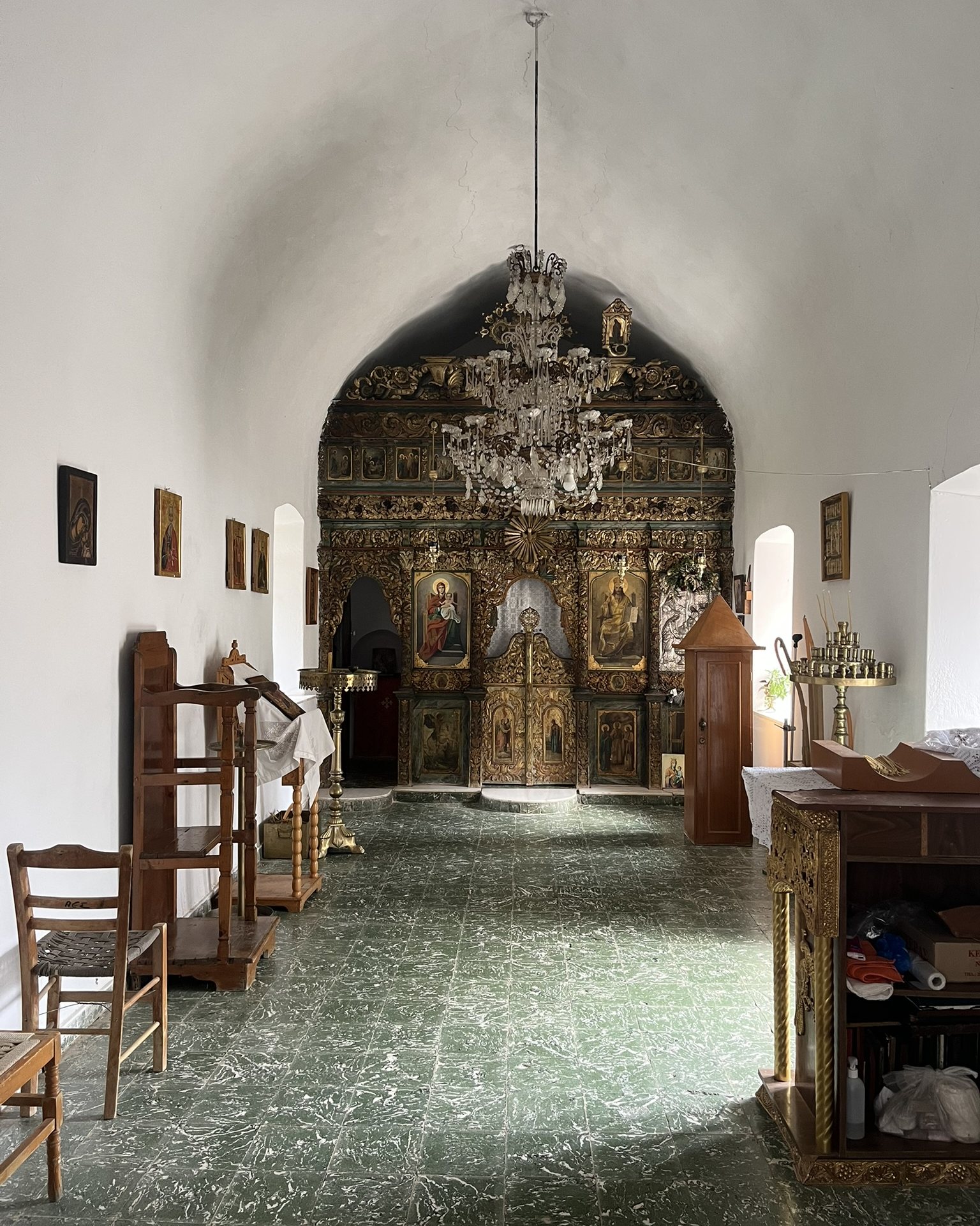 Inside Panagia Kera: a white vaulted nave, a stone floor and a carved wooden iconostasis