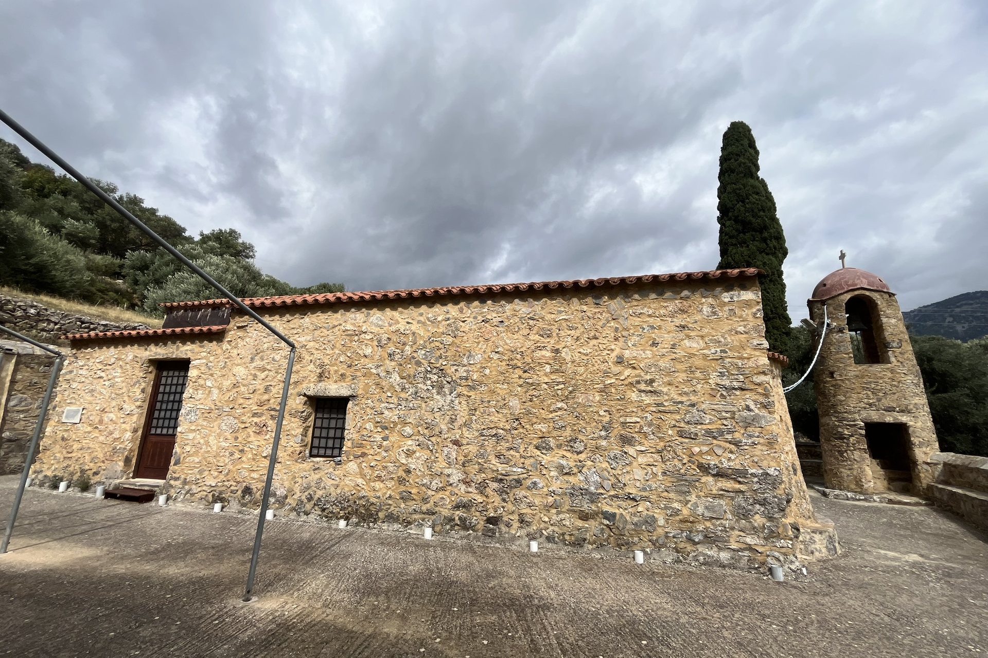 The long stone church of Agios Nikolaos near Moni with its small round bell tower and a cypress